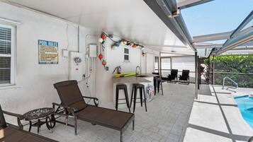 Un espace extérieur abrité comprenant une piscine, un bar, des chaises longues et un panneau indiquant les règles d’utilisation de la piscine.