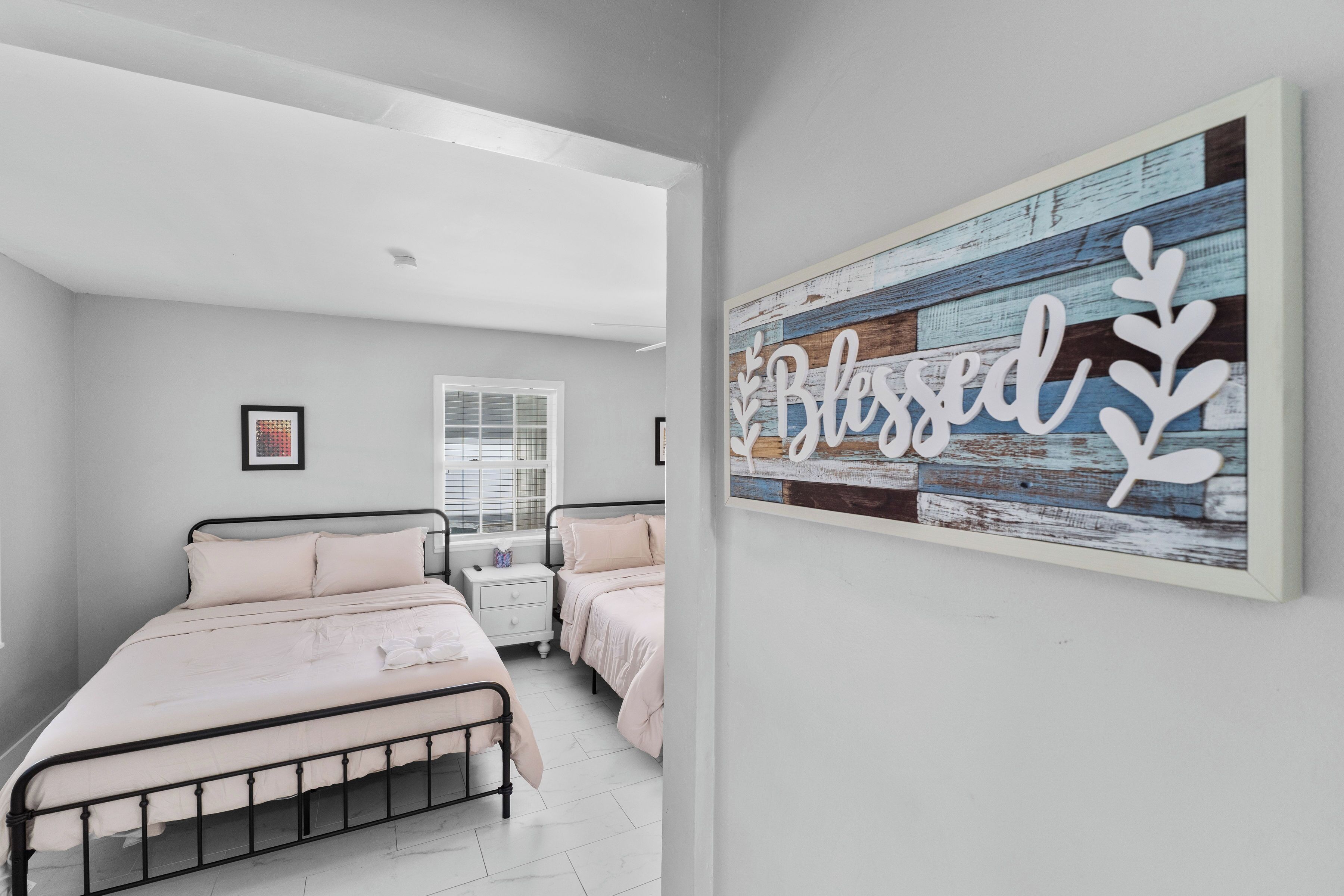 A bedroom with a bed, bedside tables, a window, and a wall-mounted artwork.