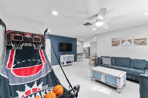 A living room with a basketball hoop, a TV, a sofa, and a coffee table.