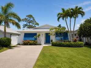 A single-story house with a white exterior, blue shutters, and a number '440' on the door. - Coastal Naples Escape Private Pool, Sleeps 12, Vanderbilt Beach 5 mins away (Naples)
