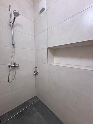 A shower with a handheld showerhead and a wall-mounted control panel. - Vrbo Property (Hamburg)
