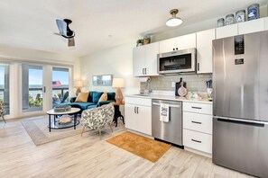 Eine moderne Küche mit Edelstahlgeräten, ein Essbereich mit Blick und ein Wohnzimmer mit Sofa und Couchtisch.