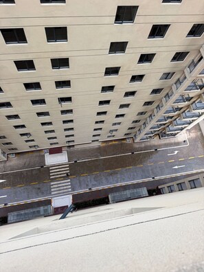 Ein Hochhaus mit mehreren Etagen, einer zentralen Treppe und einem Parkplatz mit Fahrbahnmarkierungen.