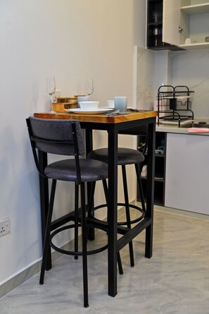 Un pequeño comedor con una mesa de madera y dos sillas negras.