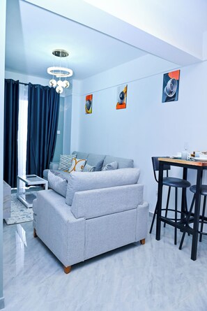 Ein modernes Zimmer mit Sofa, Esstisch, Stühlen und Kunstwerken an den Wänden.