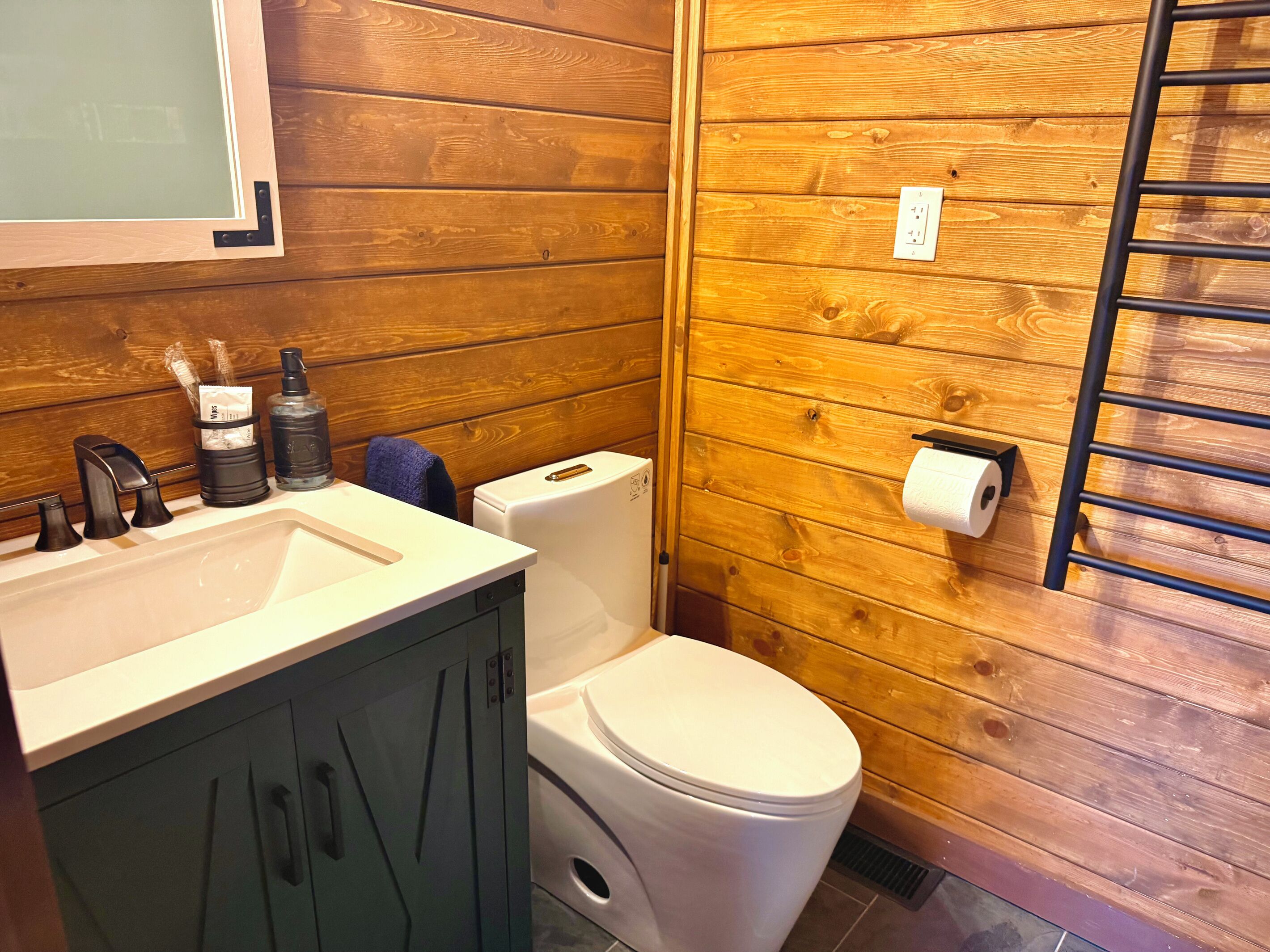 Un bagno con pannelli in legno, un lavandino bianco, un water e un portasciugamani.