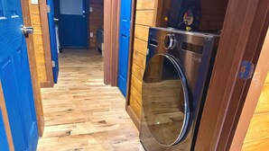 A laundry room with a stainless steel washer and dryer, wooden flooring, and blue doors. - Luxury Renovated | Pool | Hot Tub | Sleeps 20 (New Plymouth)