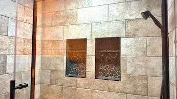 A shower with a glass door, a handheld showerhead, and a wall-mounted faucet.