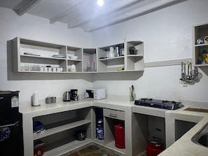 Eine kompakte Küche mit eingebauten Regalen, einer Mikrowelle, einer Kaffeemaschine und einem Gasherd.