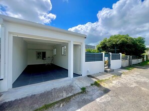 A modern building with a covered entrance, a visible window, and a paved driveway. - Vrbo Property (Les Abymes)