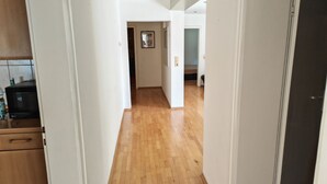 Passadís amb sòl de fusta, parets blanques i una zona de cuina amb microones i armaris.