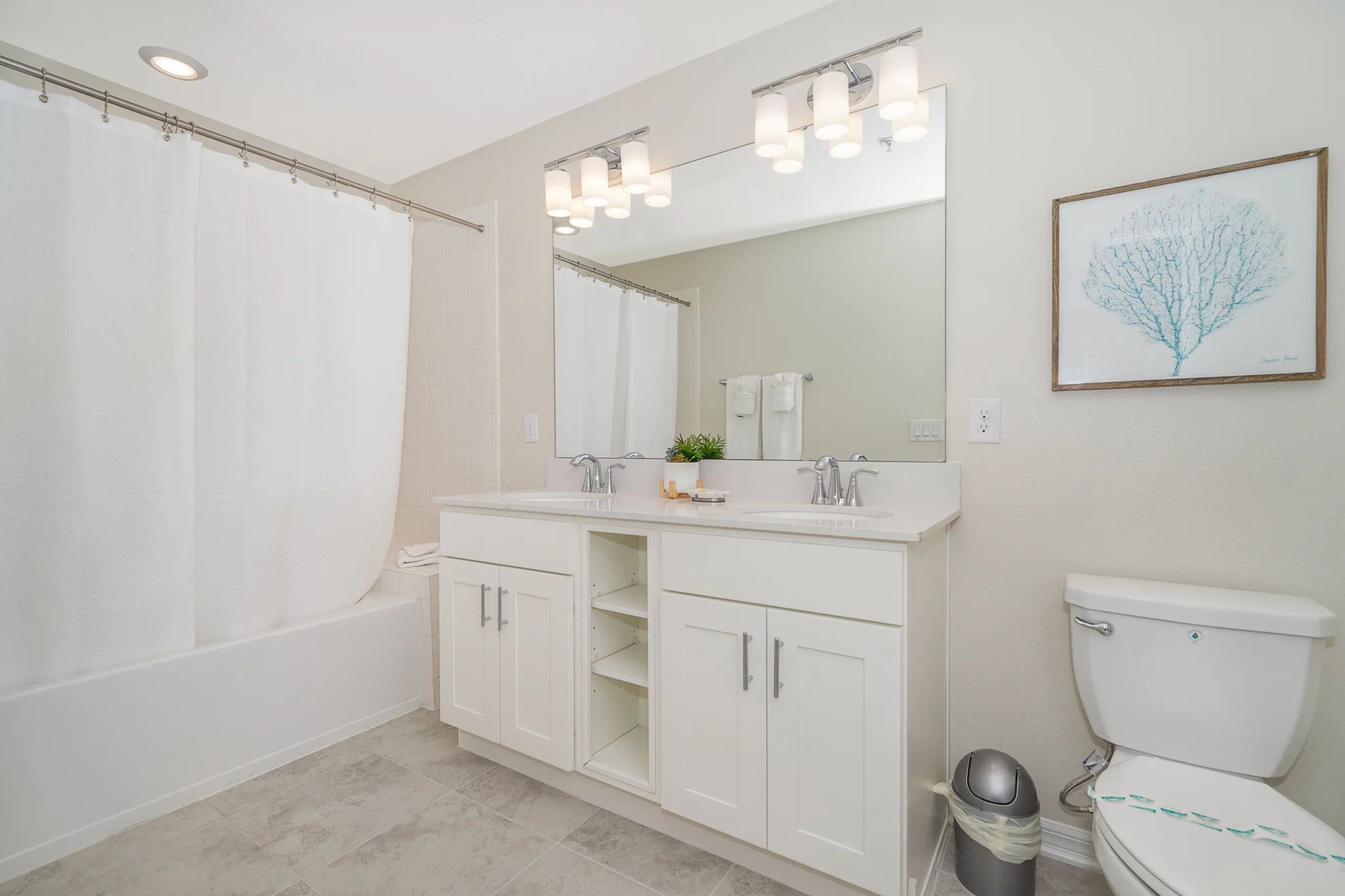 Un baño moderno con una bañera, un espejo grande, un inodoro y un lavabo.