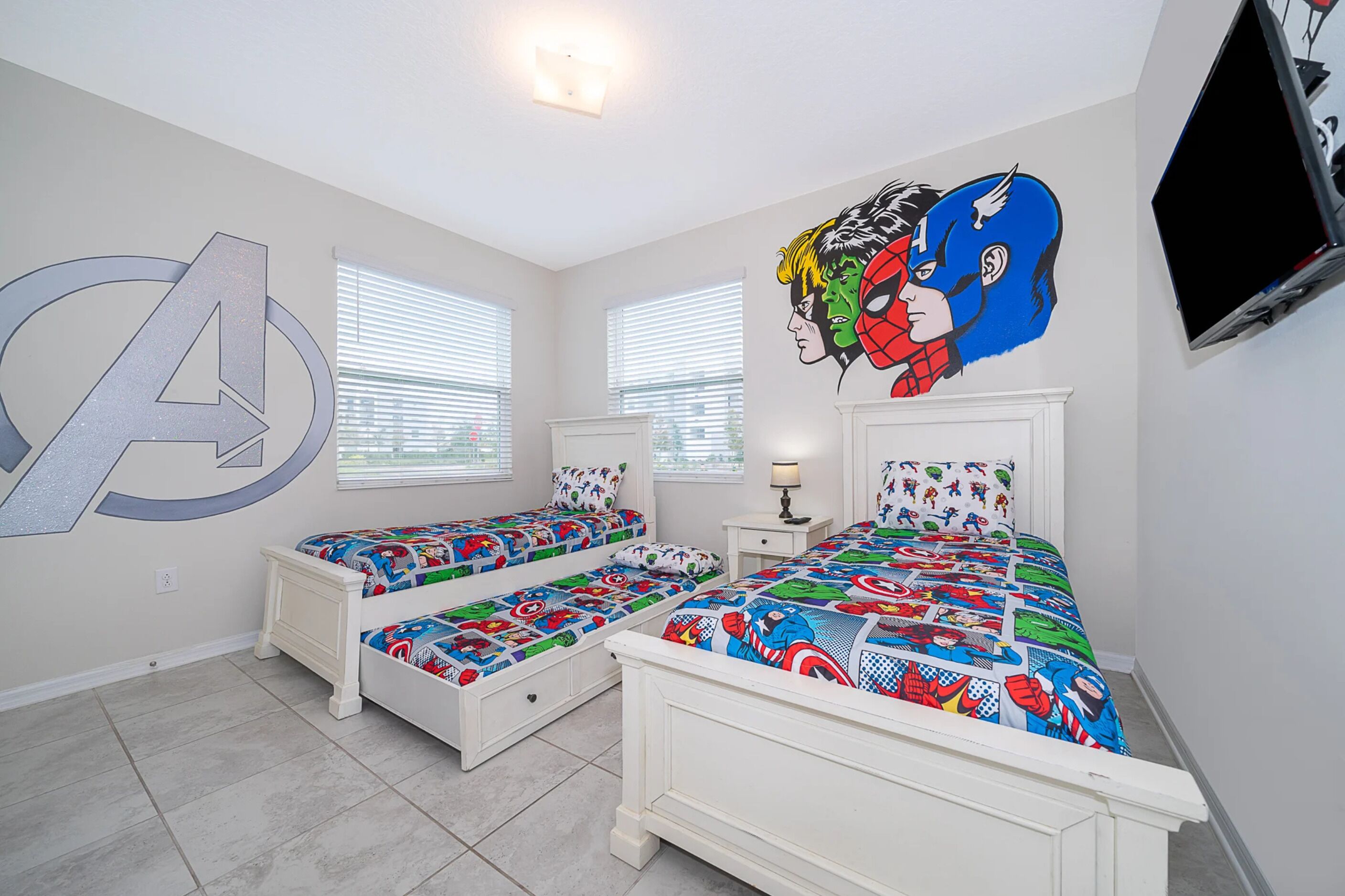 A bedroom with two beds, a large wall mural, and a television.