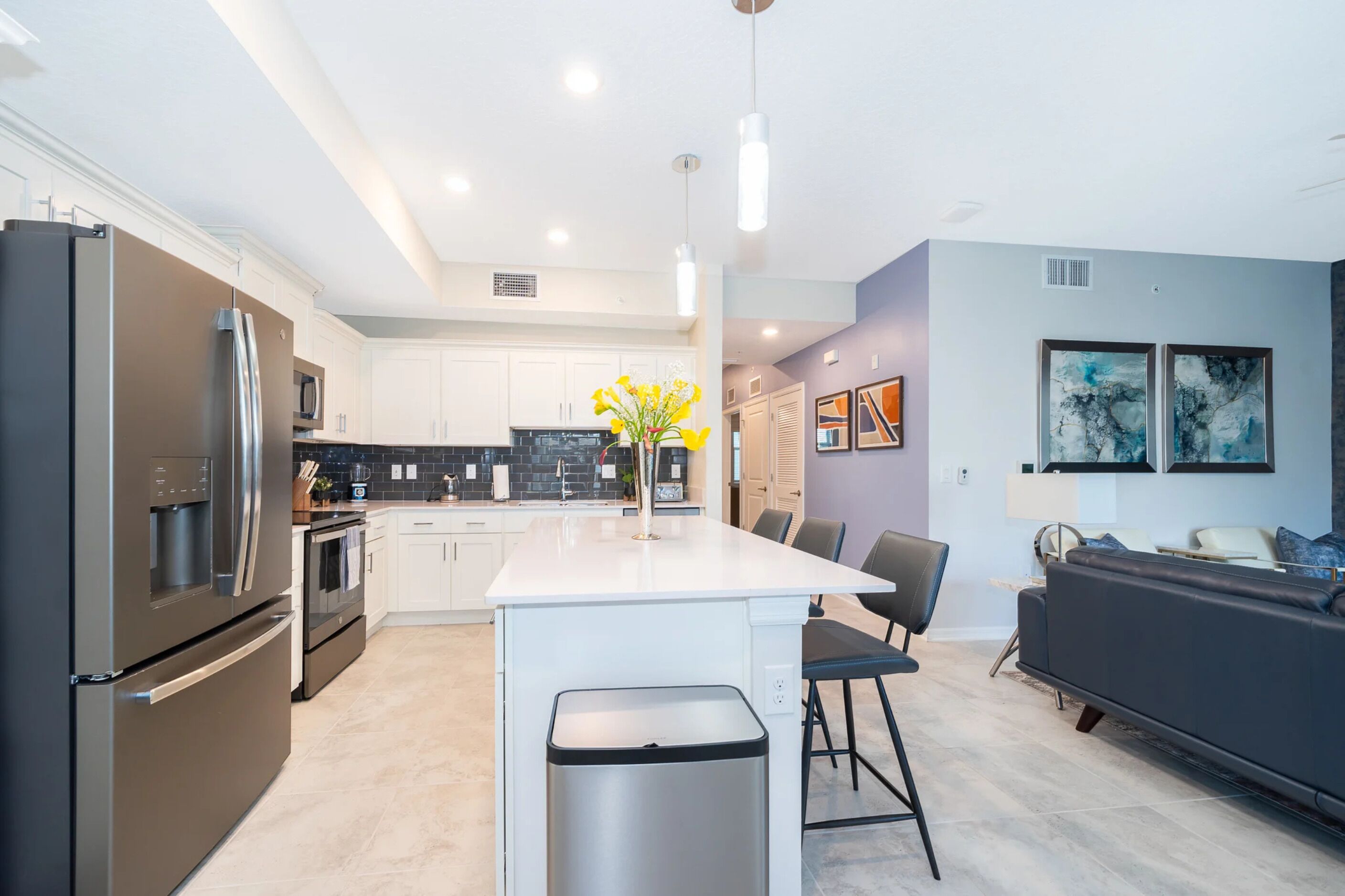 A modern kitchen with a central island, stainless steel appliances, and a seating area with a sofa and chairs.