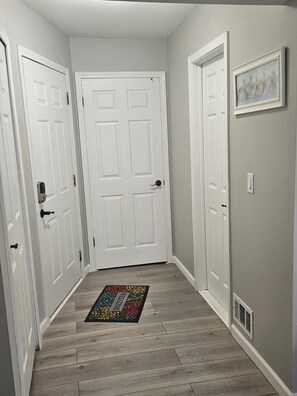 A hallway with white doors, a wooden floor, and a colorful rug.