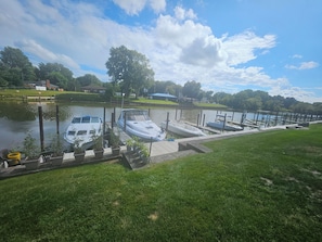 A marina with boats docked, a grassy area, and a clear sky.
