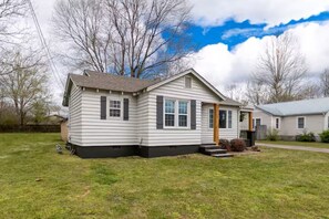 A single-story house with a front porch, a small yard, and a neighboring house.