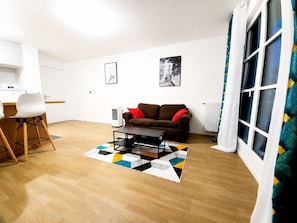 A living room with a sofa, a coffee table, a dining area with chairs, and a radiator. - Melody Clamart, 25 min from Paris, Tramway 6, Parking (Clamart)