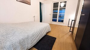 A bedroom with a bed, a window with a view, a radiator, and a door. - Melody Clamart, 25 min from Paris, Tramway 6, Parking (Clamart)