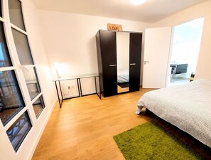 Quarto com cama, guarda-roupa, secretária e tapete verde.