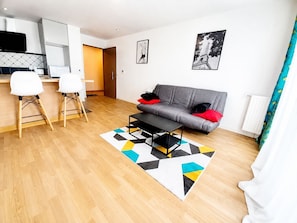 A modern living room with a grey sofa, a coffee table, and a geometric rug. - Melody Clamart, 25 min from Paris, Tramway 6, Parking (Clamart)