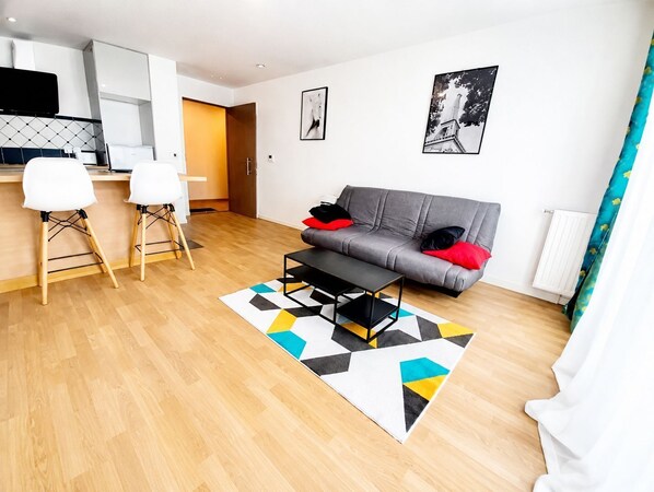 Uma sala de estar moderna com um sofá cinzento, uma mesa de centro e um tapete geométrico.