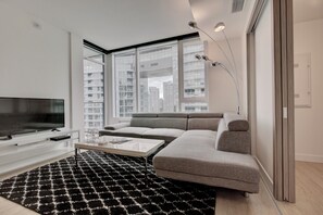 Een moderne woonkamer met een flatscreen televisie, een bank, een bijzettafeltje en een kamerkleed met dessin.