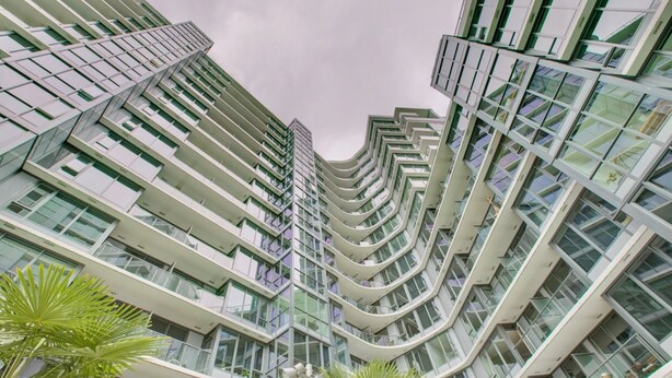 Un edificio moderno de gran altura con múltiples balcones y ventanas amplias.
