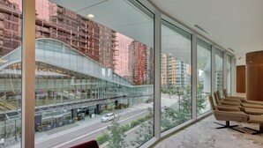 Un vestíbulo de hotel con ventanas amplias, fachada de vidrio curvo y vista a una calle de la ciudad.