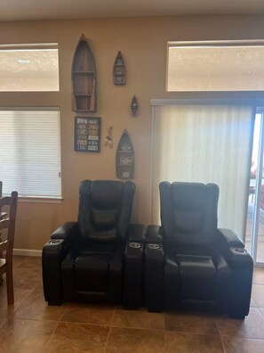 Une pièce comprenant deux fauteuils de massage, une étagère en bois ornée d’objets décoratifs et un panneau indiquant des numéros.