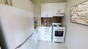 A compact kitchen with white cabinets, a stove, an oven, and a coffee maker. - 1 Bedroom Apt available Downtown Toronto,15 minutes to CN Tower (Toronto)