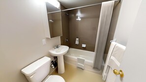 Ein Badezimmer mit Toilette, Waschbecken, Badewanne und Dusche.