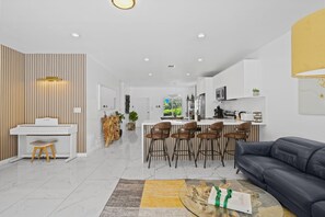 Ein modernes Wohnzimmer mit einem Klavier, einer Couch und einem Essbereich mit Barhocker.