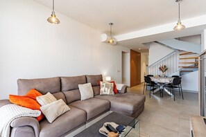 A modern living room with a sofa, coffee table, and dining area. - Premium Penthouse · Private Terrace · Ocean View (Adeje)