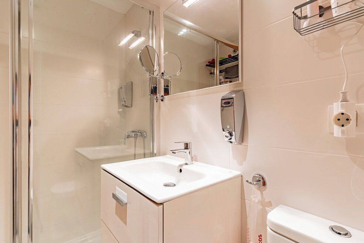 Une salle de bain moderne avec une douche à parois de verre, un lavabo blanc et des toilettes.