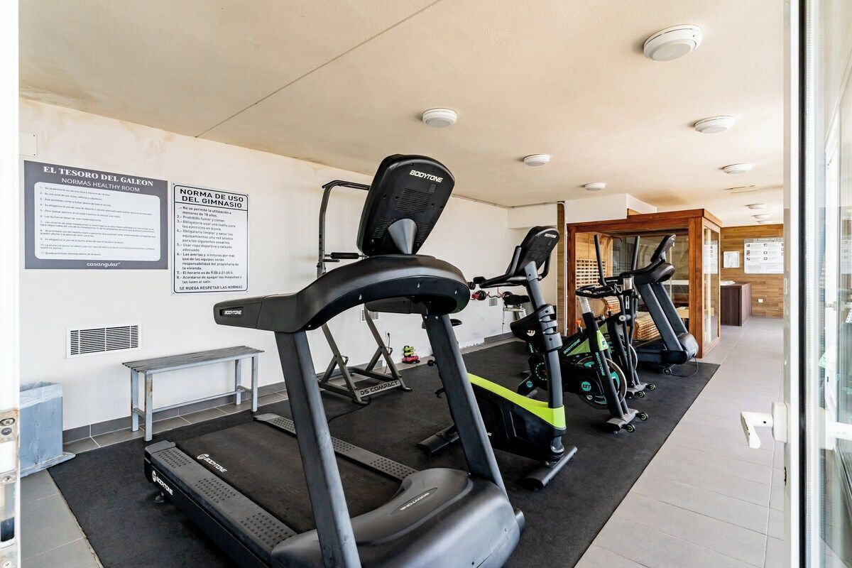 A gym with treadmills, stationary bikes, and a weight bench.