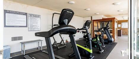 A gym with treadmills, stationary bikes, and a weight bench.