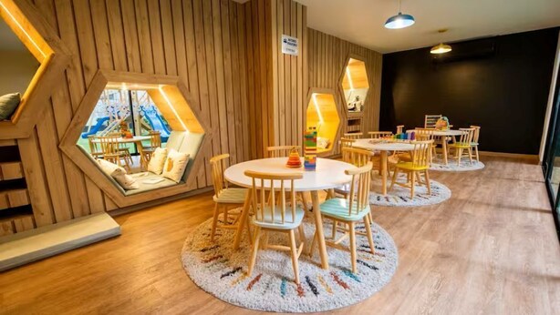 Une pièce dotée de fenêtres hexagonales, de murs en bois et d’une table ronde entourée de chaises.