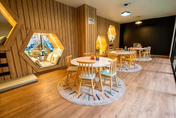 Ein Zimmer mit sechseckigen Fenstern, Holzwänden und einem runden Tisch mit Stühlen.