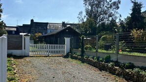 A gravel driveway leading to a gated entrance with a wooden building in the background. - Superb house 85m² - Beaches 2km away - Enclosed garden (Billiers)