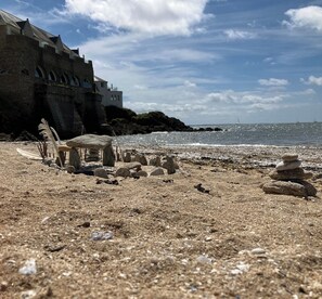 A beach with a stone structure, a building with arched windows, and a clear sky. - Superb house 85m² - Beaches 2km away - Enclosed garden (Billiers)
