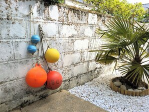 A concrete wall with colorful buoys and a palm plant. - House 80m² center ville - Beach 250m, private courtyard (Damgan)