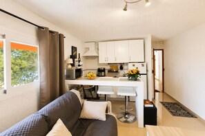 A compact living space with a kitchenette, a sofa, a dining area, and a view of the outdoors. - Cozy apartment on the sea shore (Costa de la Calma)