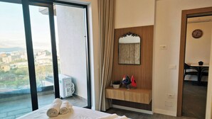 Ein Hotelzimmer mit Bett, Schminktisch mit Spiegel, Blick auf die Stadt und Schreibtisch mit Stühlen.