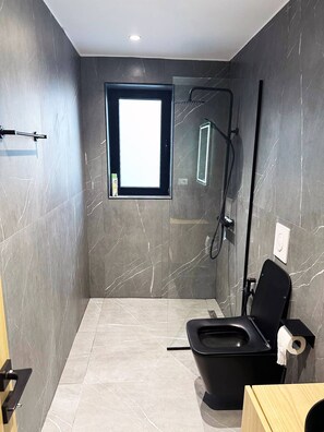 Ein modernes Badezimmer mit Toilette, Dusche und kleinem Fenster.