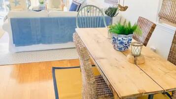 A dining area with a wooden table and wicker chairs, a blue and white patterned vase, and a hanging lantern.