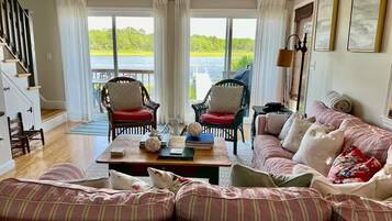 Un salon comprenant un canapé, deux fauteuils, une table basse et une vue sur un lac, visible à travers de grandes fenêtres.