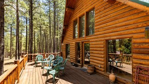 Une cabane en bois dotée d’une terrasse, de meubles d’extérieur et d’une grande fenêtre.