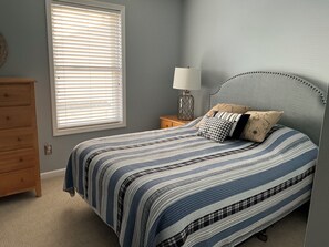 A bedroom with a bed, a dresser, a nightstand with a lamp, and a window with blinds. - Spacious 3 Bedroom 2 Full baths in Wildwood Crest. 3 Blocks from to the beach. (Wildwood)
