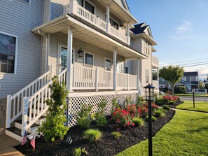 A two-story house with a front porch, a small garden with flowers and shrubs, and a street lamp. - Spacious 3 Bedroom 2 Full baths in Wildwood Crest. 3 Blocks from to the beach. (Wildwood)
